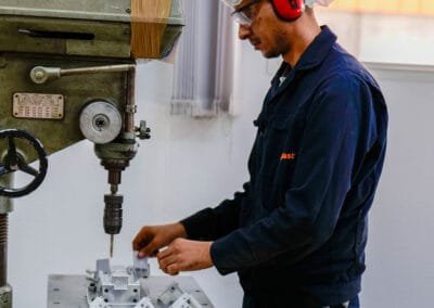 AXOPLAST technician machining a mould component on a pillar drill