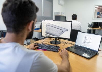 AXOPLAST engineer reviewing a 3D part design on a CAD workstation